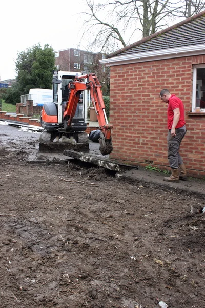 Un mini scavatore che scava un vialetto — Foto Stock