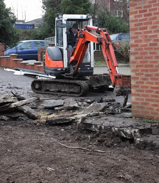 Una mini excavadora excavando un camino de entrada — Foto de Stock