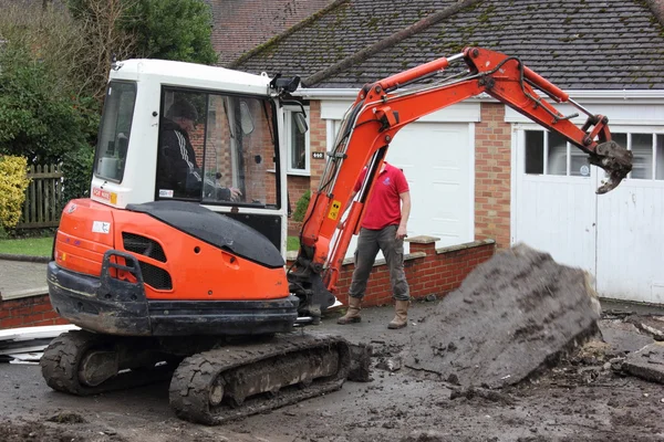 Una mini excavadora excavando un camino de entrada —  Fotos de Stock