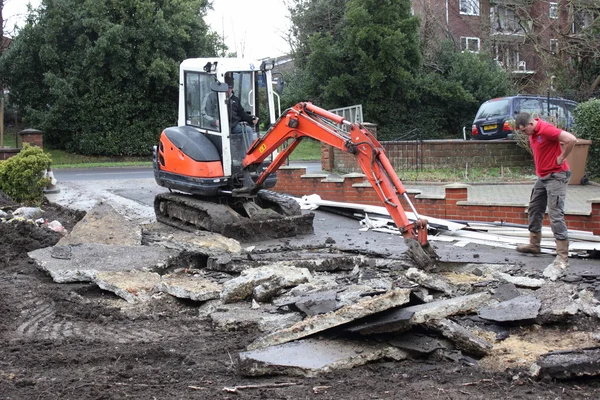 Una mini excavadora excavando un camino de entrada — Foto de Stock