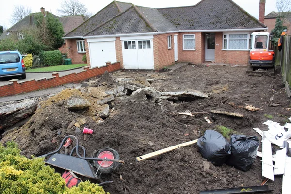 Una mini excavadora excavando un camino de entrada — Foto de Stock