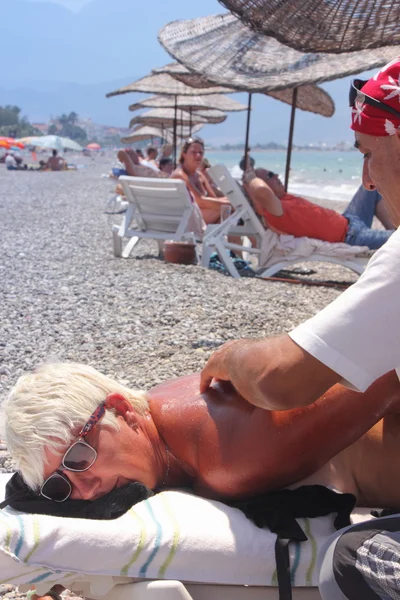 Masseur gibt einer schönen Frau am Strand eine Vollmassage — Stockfoto