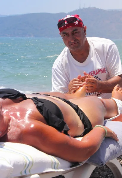 Masseur giving a full massage to a beautiful woman on the beach — Stock Photo, Image