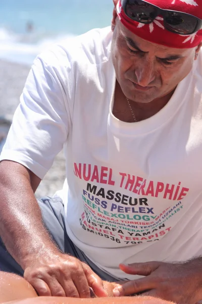 Masseur giving a full massage to a beautiful woman on the beach — Stock Photo, Image