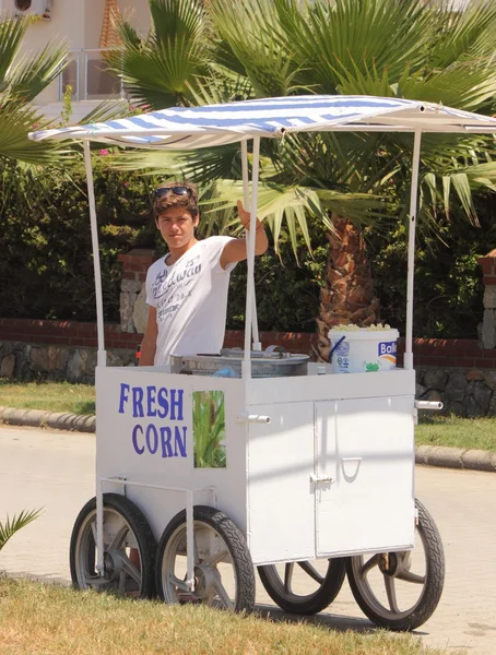 An unknown young male street vendor selling his fresh corn on the cob — Stock Photo, Image