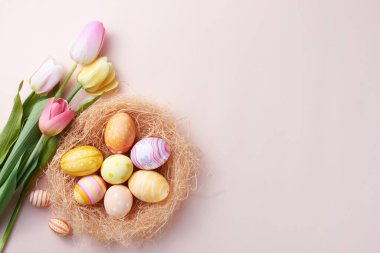 Mutlu Paskalya günleri. Yuvadaki renkli yumurtalar ve fotokopi alanı olan kağıt arka plan çiçekleri..