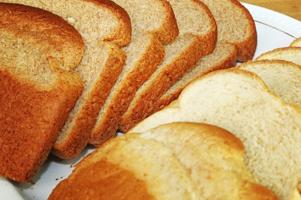 Plaka üzerinde açık ve koyu buğday ekmek dilimleri — Stok fotoğraf
