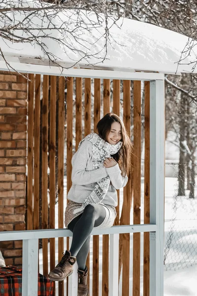 Kadın kış boyunca evin terasında oturuyor..