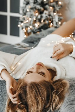 Kadın rahatladı. Yılbaşı ağacının yanındaki yatakta yatıyor..