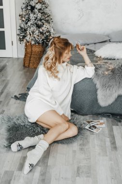 Kadın Noel ağacının yanında, yatağın yanında oturuyor..