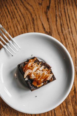 Brownie with almonds is already  eaten placed on a wooden table 