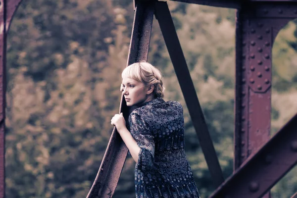 Ung flicka står på bron uthärda — Stockfoto
