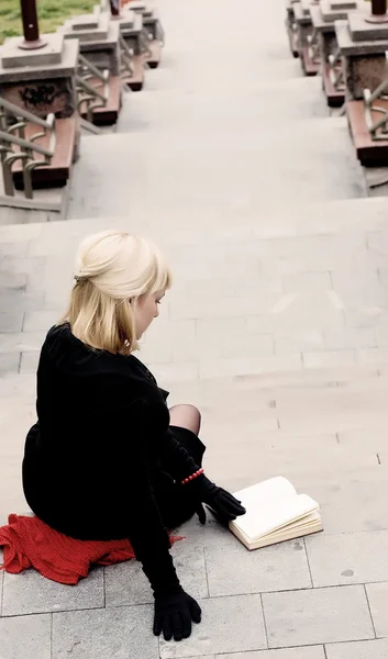 Nő ül a lépcsőn, és egy könyvet olvas — Stock Fotó