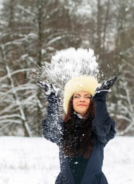 Genç bayan karla oynuyor.