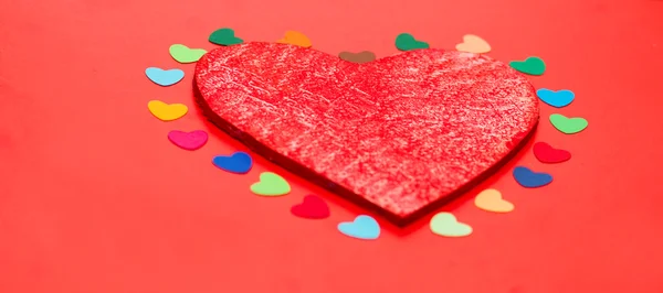 Hogares de papel multicolor alrededor de un corazón rojo de madera — Foto de Stock