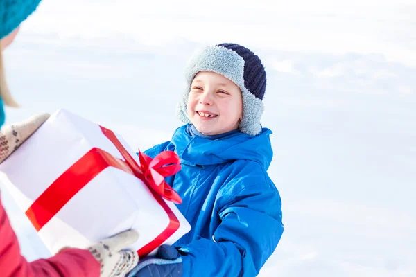 Kvinna ger en jul närvarande pojke — Stockfoto