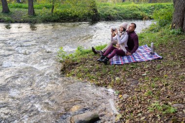 Bir adam ve bir kız nehir kenarında çay içiyorlar.