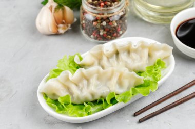 Japon ya da Çin yemeği, haşlanmış gyoza köftesi et ya da sebze ile doldurulmuş salata yaprakları. Işık arkaplanına yakın plan.
