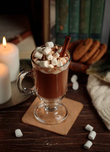 Kakao oder heiße Schokolade mit Marshmallows auf einem Holztisch, mit Büchern, Keksen, einer Decke und brennenden Kerzen. Vertikal, leise — Stockfoto