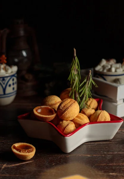 Galletas en forma de nueces con leche condensada relleno en un tazón en forma de estrella, decorado con romero árboles de Navidad. — Foto de Stock