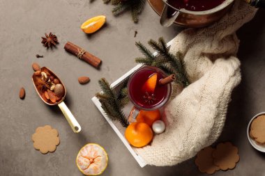 Tarçın çubuğu, ekose örgü, mandalina ve köknar dallarıyla süslenmiş bir bardak sıcak şarap. Düz Yatay