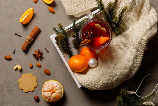 Glegs o vino caliente en una taza de vidrio, en una bandeja con una manta de punto, mandarinas y ramas de abeto. — Foto de Stock