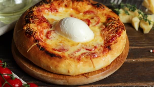 The cook sprinkles parmesan and decorate with thyme homemade pizza with a ball of mozzarella and baked crust — стоковое видео