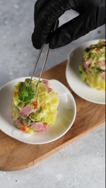 Дизайн еды. Шеф-повар в перчатках украшает часть салата петрушкой и яйцом перепела с помощью пинцета — стоковое видео