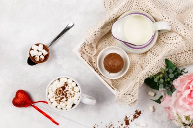 Romantik kahvaltı, sürpriz. Çikolata bombası, marşmelovlu kakao, bir sürahi süt ve kalpli bir buket. Üst görünüm.