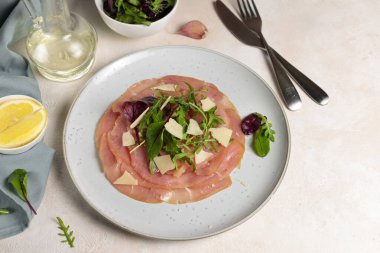 Et aperatifi carpaccio, roka salatası ve parmesan dilimleri. Yatay, hafif bir yüzeyde, yemek pişirmek için gerekli malzemeler var..