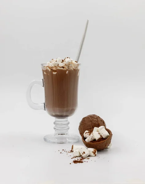 Bombas de chocolate con malvaviscos para hacer cacao y un vaso con una bebida preparada sobre un fondo blanco. — Foto de Stock