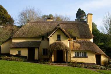 Thatched cottage in an English village clipart