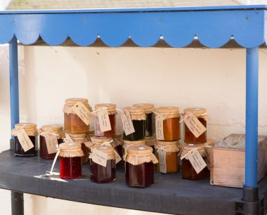 Home made jams and preserves for sale in pots with labels and honesty box for payment clipart