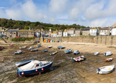 Boats in Mousehole harbour Cornwall England Cornish fishing village with blue sky and clouds at low tide clipart