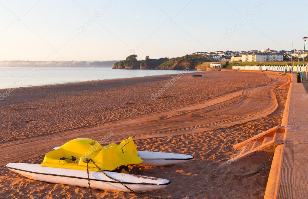 Goodrington beach near Paignton Devon England with colourful beach huts on a summer morning with pedalos on the beach