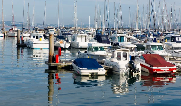 Motor boats in a marina with masts and calm blue sea — Stock Photo, Image