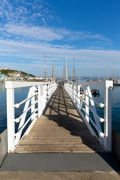 Pasarela de embarcadero de madera blanca al puerto deportivo con cielo azul y nubes — Foto de Stock