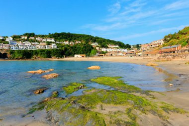 Yeşil yosun mavisi deniz ve gökyüzü ile Looe plajı Cornwall
