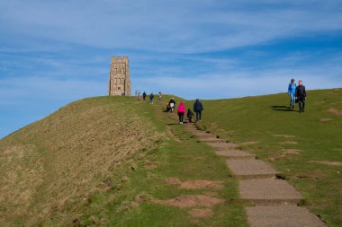 Kış fırtınalarının ardından 26 Şubat 2022 tarihinde Glastonbury Tor, Somerset 'e gelen ziyaretçiler güzel güneşli havanın tadını çıkardılar.