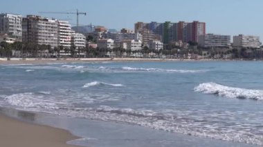Akdeniz dalgaları sahile vuruyor. Villajoyosa İspanya. Arka planda daireleri olan Costa Blanca.