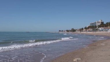Akdeniz dalgaları sahile vuruyor. Villajoyosa İspanya. Arka planda daireleri olan Costa Blanca.