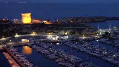 El Campello İspanya Kulesi ve marina geceleri Costa Blanca turistik merkezi. Arka planda Benidorm ışıkları parlıyor.