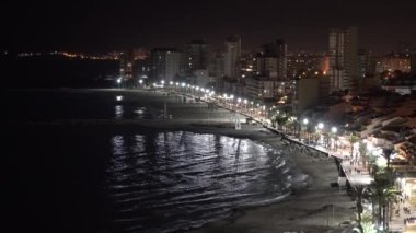 Gece vakti El Campello Costa Blanca kıyı kasabası İspanya Parlak ışıkları, palmiye ağaçları, deniz ve gece vakti uzak insanlar