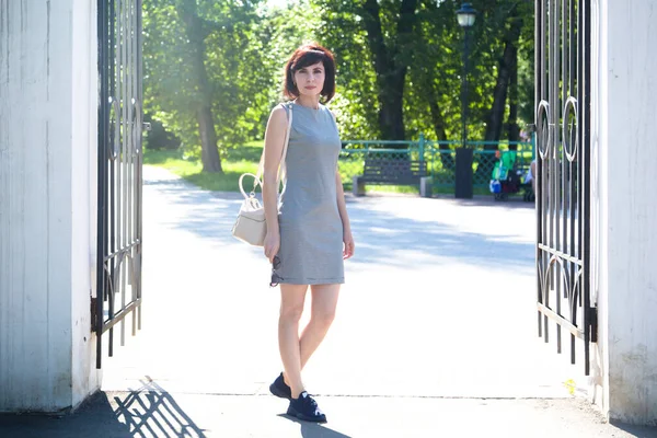 Uma Mulher Vestido Listrado Curto Está Nos Portões Abertos Parque — Fotografia de Stock