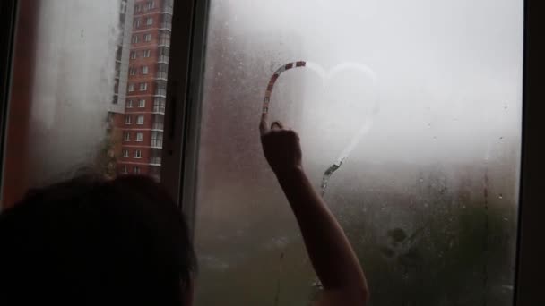 Una Chica Dibuja Corazón Con Dedo Una Ventana Niebla Concepto — Vídeo de stock