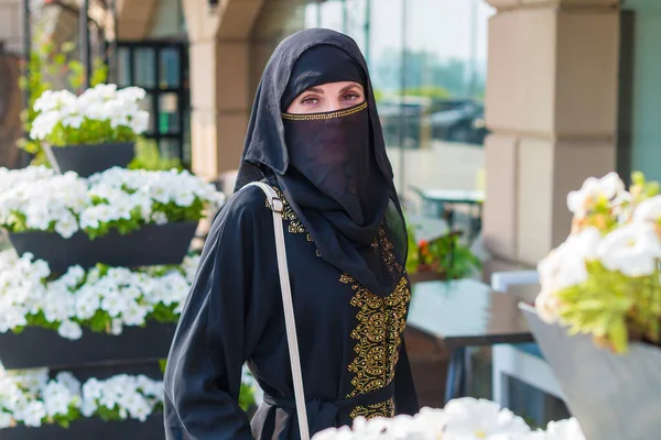 美しい白い花の間の通りに民族衣装の若いイスラム教徒の女性の肖像画 — ストック写真
