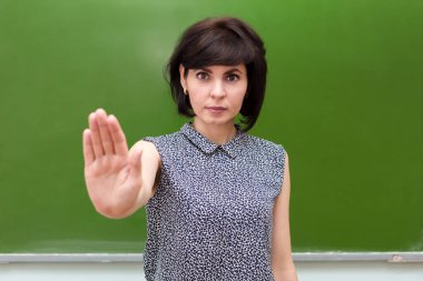 Okulun karatahtasında katı bir öğretmen okulda şiddete dur işareti gösterir..