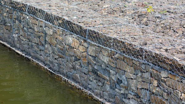 用金属网中的石头视频模糊了河水 加固河岸 — 图库照片