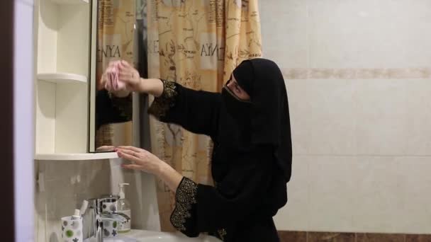 ムスリム女性主婦はバスルームミラーからほこりを拭く — ストック動画