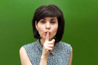 Öğrencileri sakinleştirmeye çalışan tahtadaki öğretmen parmağını dudaklarına dayayarak sessizlik işareti gösteriyor..